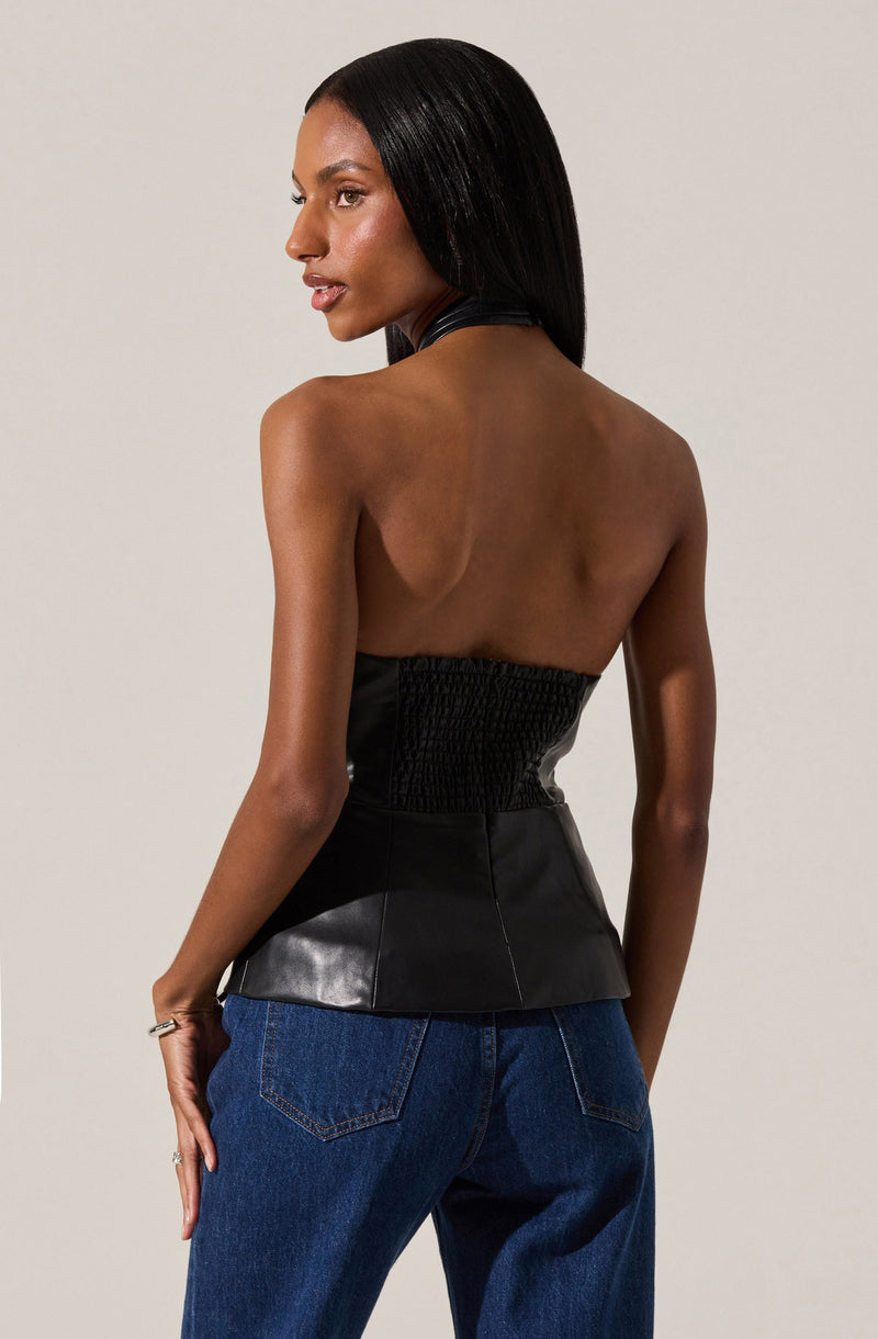 A woman is wearing a sleeveless black top with a high neckline and a fitted, smocked bodice that flares out slightly at the waist. She is also wearing blue jeans with visible stitching on the back pockets.