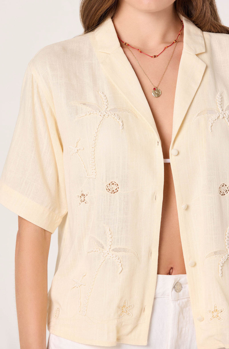 Light yellow short-sleeve button-up shirt with palm tree embroidery and eyelet details.