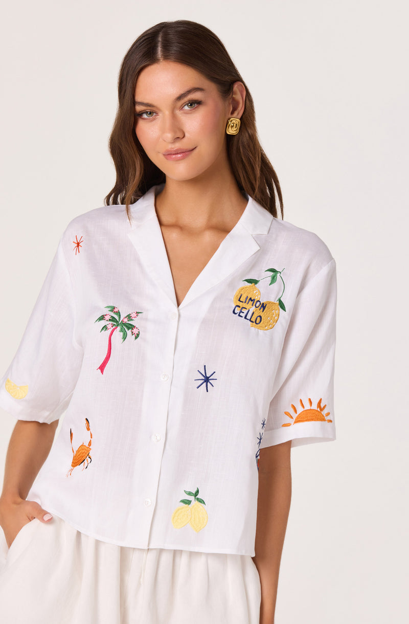 White short-sleeve button-up shirt with colorful embroidered tropical and fruit designs.