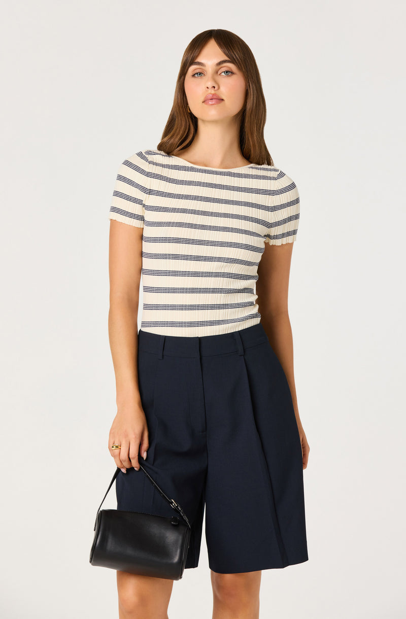 Woman wearing a short-sleeve striped top and navy wide-leg shorts, holding a black handbag.