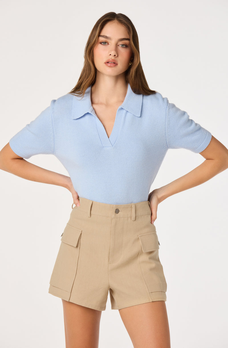 Light blue short-sleeve collared knit top and beige high-waisted cargo shorts.