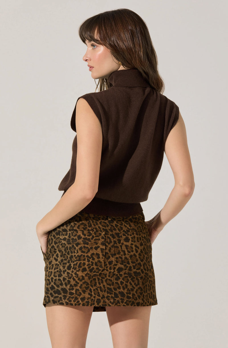 A woman is wearing a sleeveless, dark brown high-neck top paired with a leopard print skirt featuring a drawstring waist.