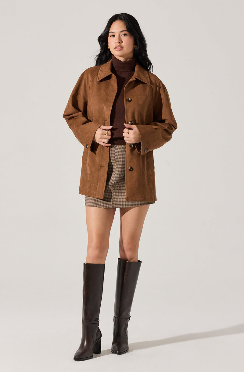 A woman is wearing a brown suede button-up jacket with a collar, over a dark brown turtleneck sweater. She has on a beige and brown checkered mini skirt and tall dark brown leather knee-high boots.