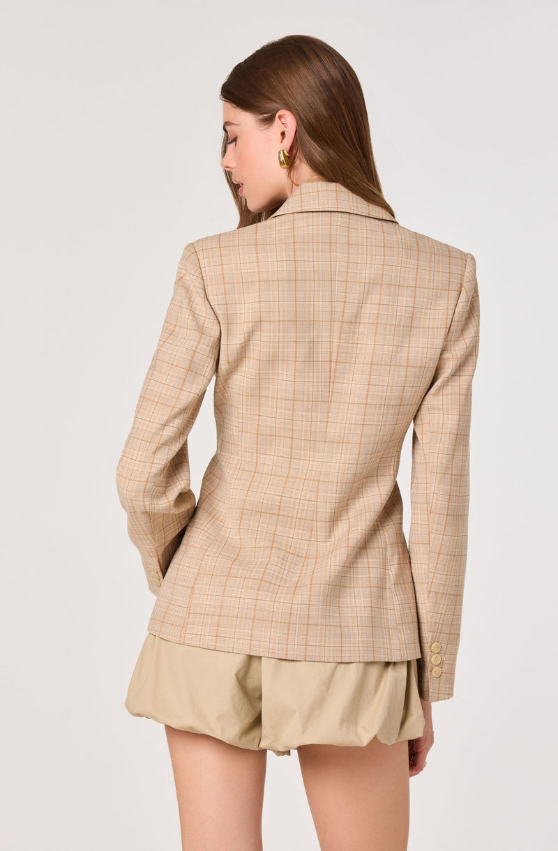 Woman wearing a beige checkered blazer and beige puffed shorts, facing away.