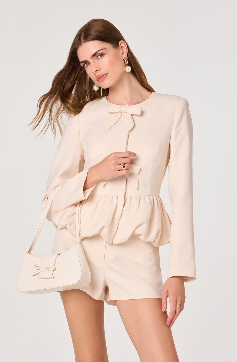 Cream-colored blazer with a bow at the neckline and matching shorts.