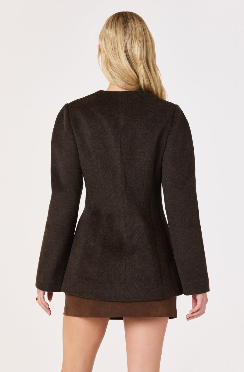 Woman wearing a dark brown blazer and a brown skirt, viewed from the back.