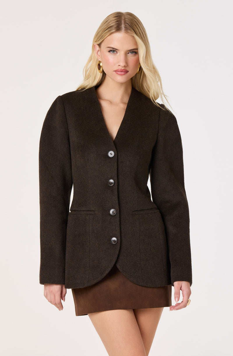 Woman in a dark brown tailored blazer with large buttons and a mini skirt.