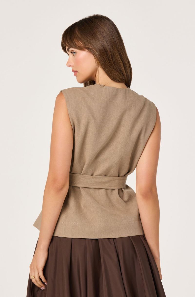 Beige sleeveless vest with a matching belt, paired with a dark brown pleated skirt.