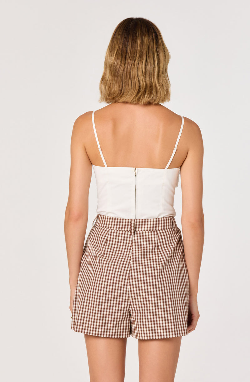White spaghetti strap top with zipper back, paired with beige and brown gingham shorts.