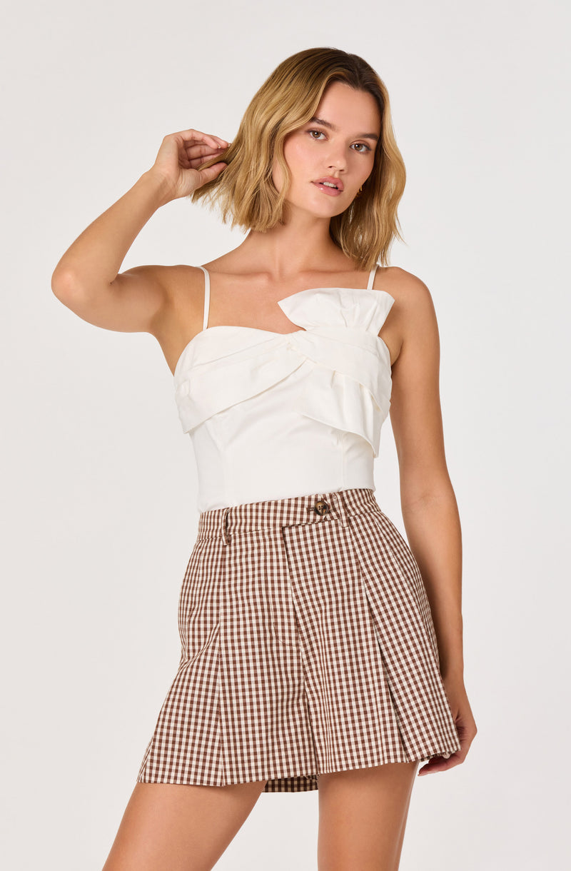 White spaghetti strap top with ruffle detail, brown and white gingham skirt.