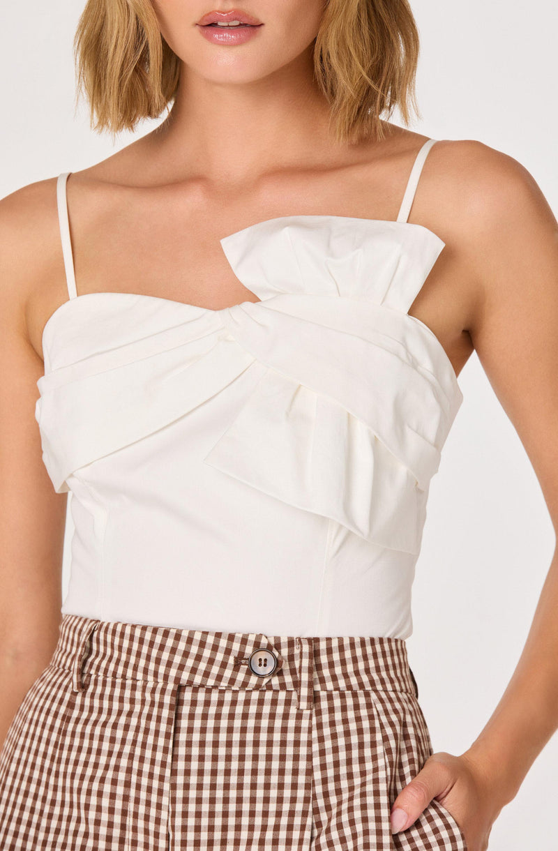 White ruffled sleeveless top with thin shoulder straps and gingham high-waisted pants.