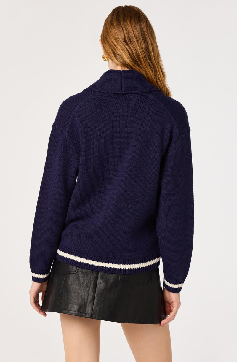Woman wearing a navy blue knitted sweater with white stripes at the hem and cuffs.