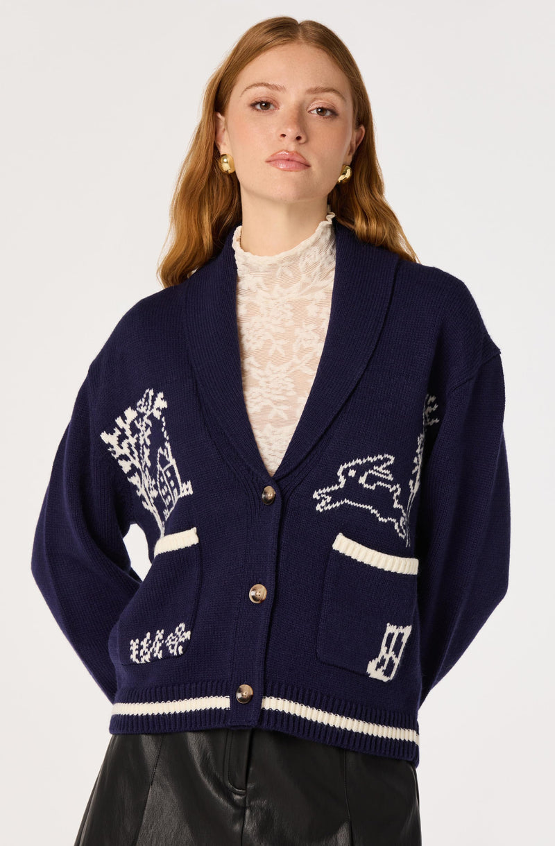 Woman wearing a navy blue cardigan with white snowflake, tree, and animal patterns, and beige buttons.