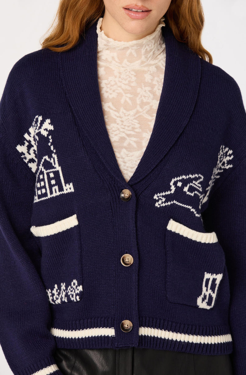 Woman wearing a dark blue cardigan with white holiday-themed patterns and beige buttons.