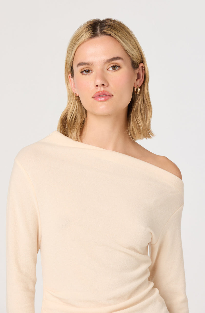 Woman in a cream off-shoulder top with long sleeves.