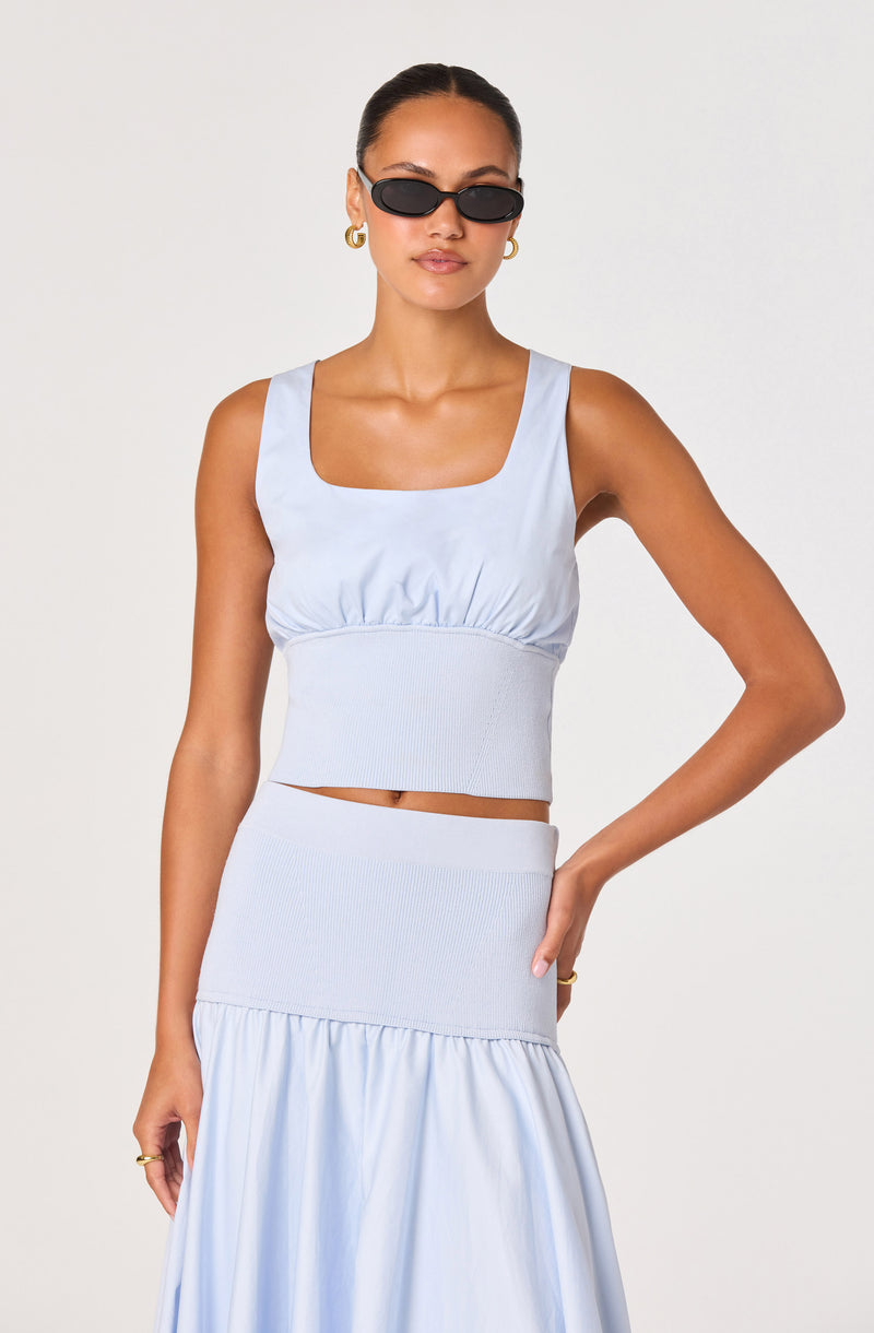 Model wearing a light blue tank top and matching skirt with ruffle detail.