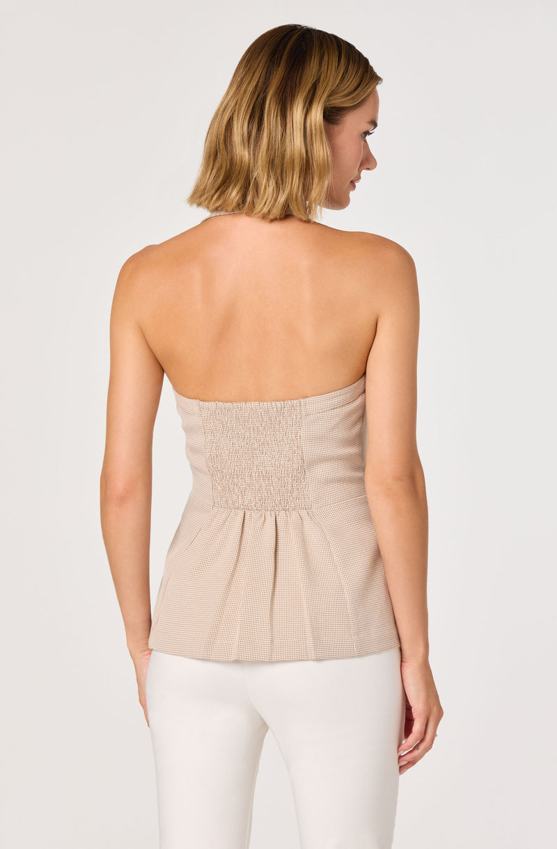 Beige strapless top with smocked waist and pleated hem, worn with white pants.