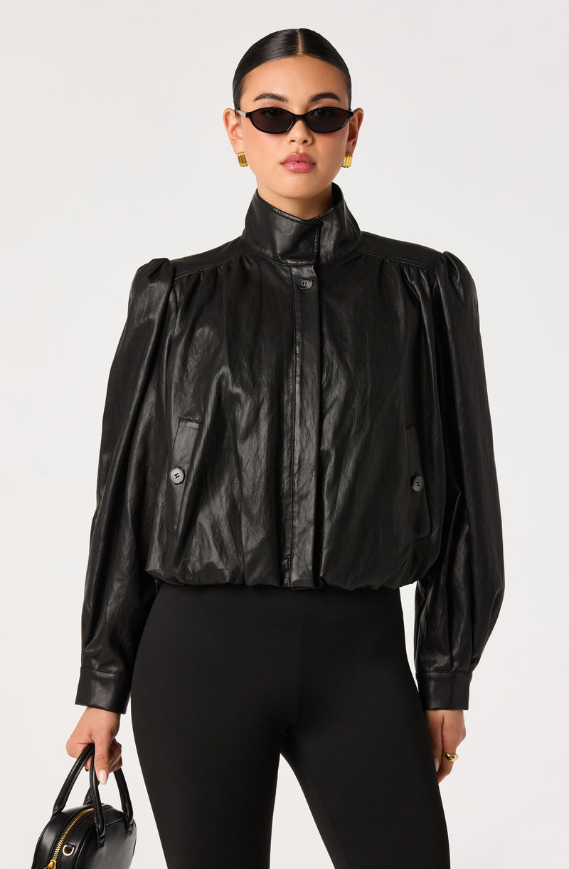 Woman in a black leather jacket with puffed sleeves and high collar, paired with black pants.