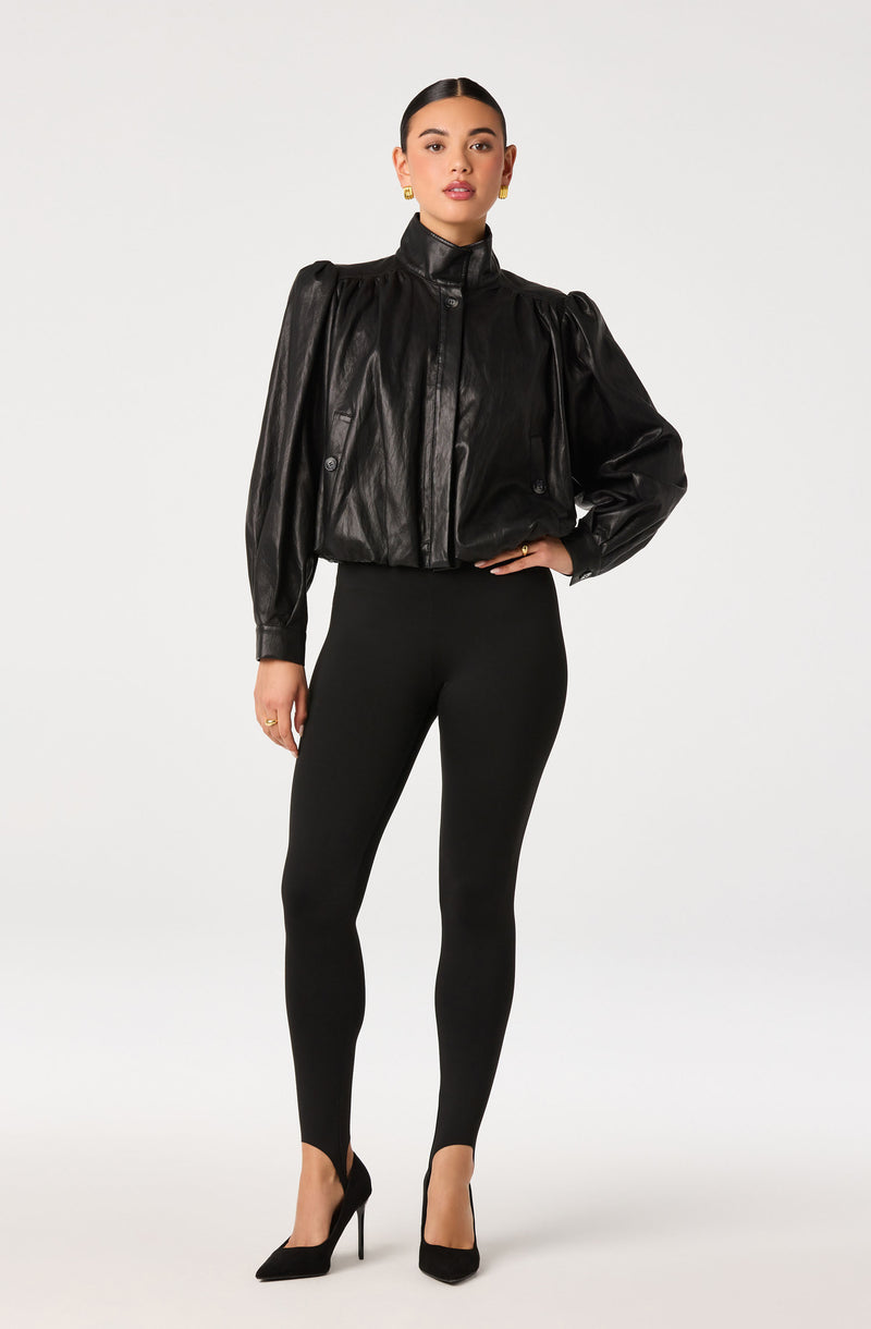 Woman in a black leather jacket, black leggings, and black high heels.