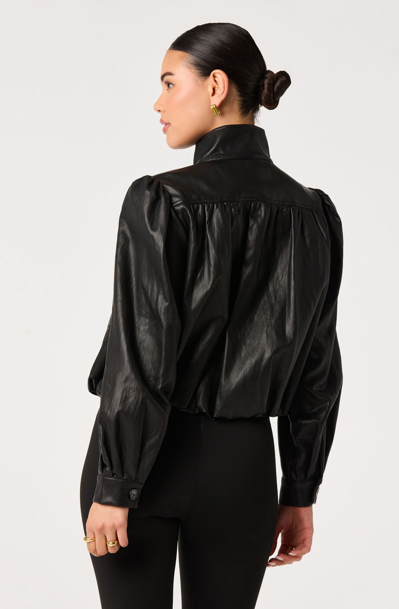 Woman wearing a black leather cropped jacket with puffed sleeves and high collar.