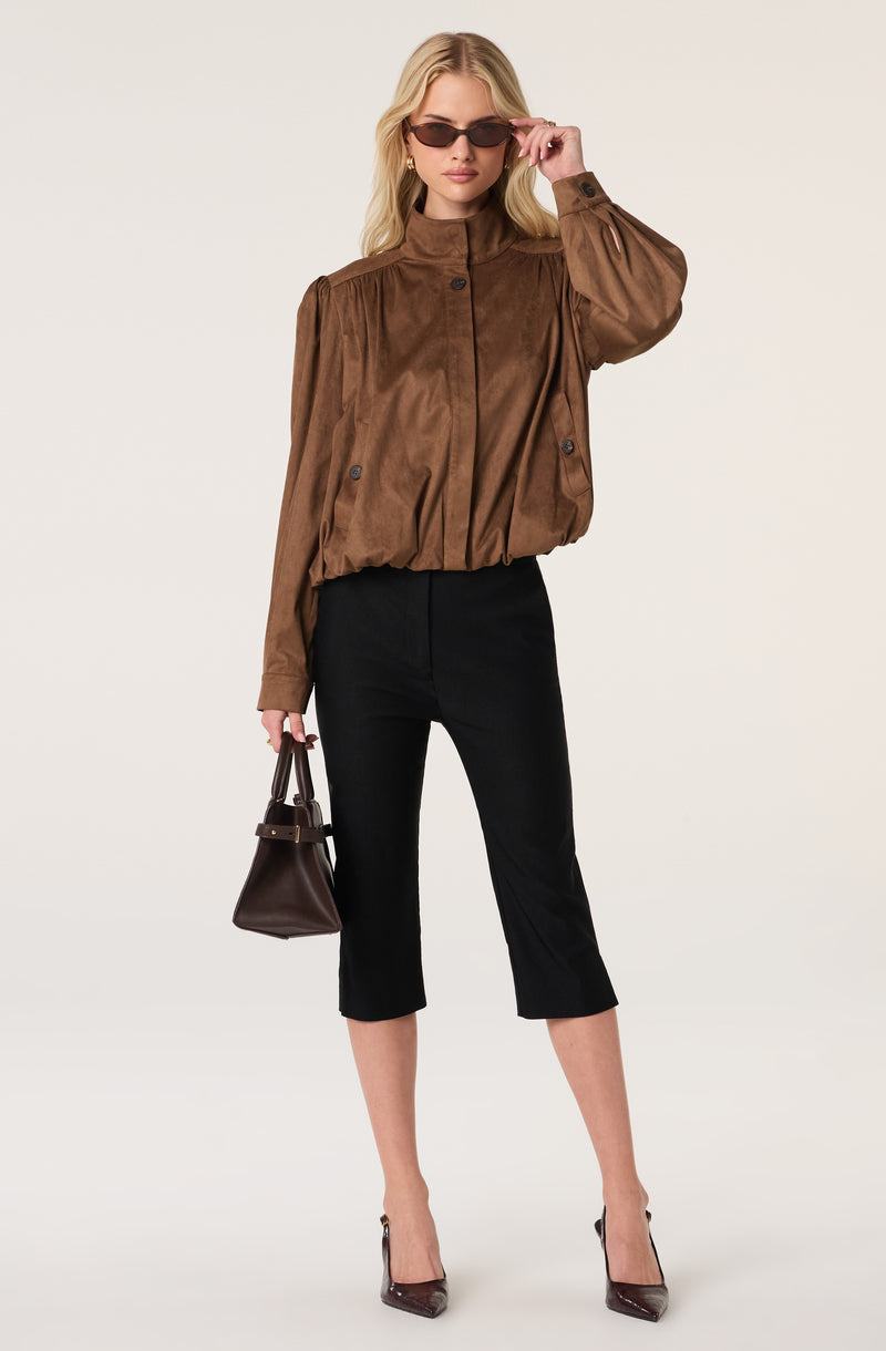 Woman wearing a brown oversized jacket, black cropped pants, and brown high heels.
