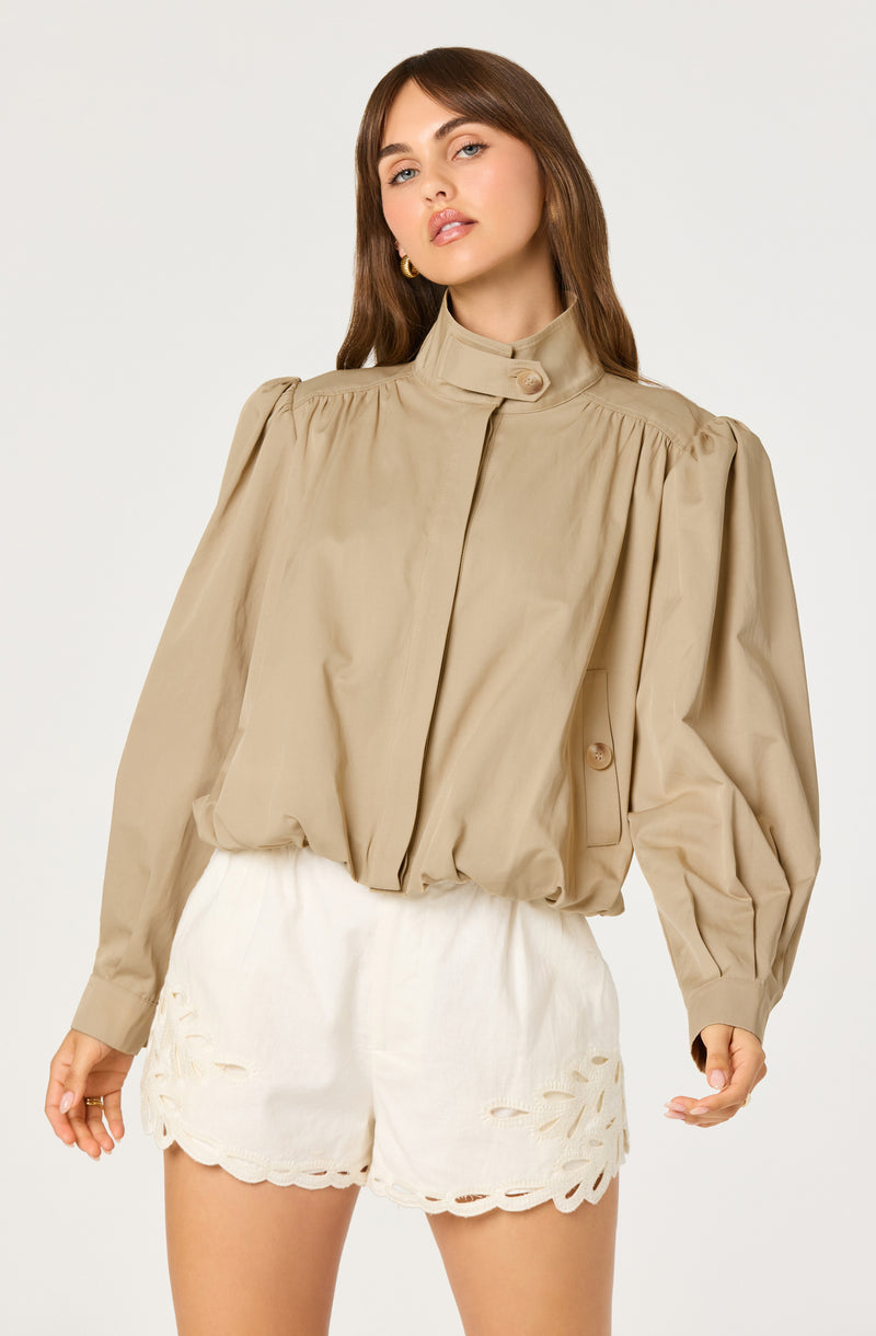 Beige puff-sleeve blouse with a high collar and button detail, paired with white embroidered shorts.