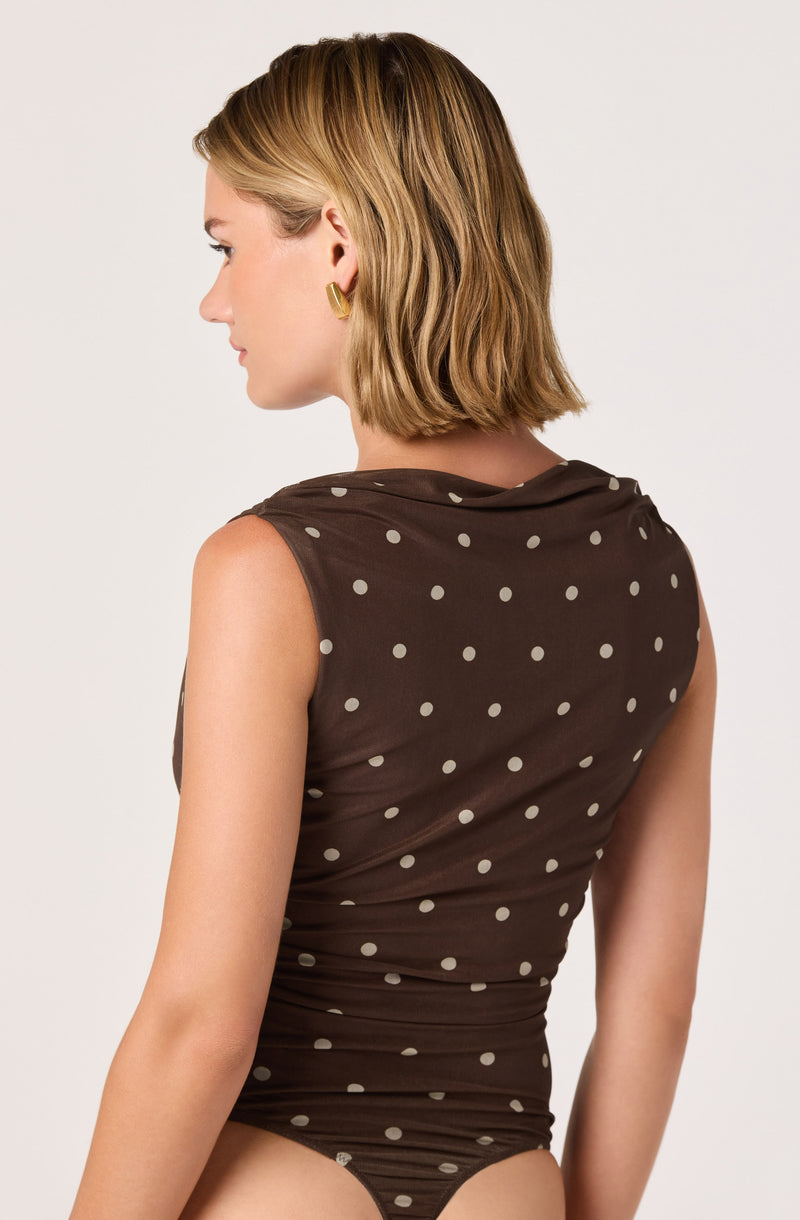 Woman in a sleeveless brown bodysuit with beige polka dots.