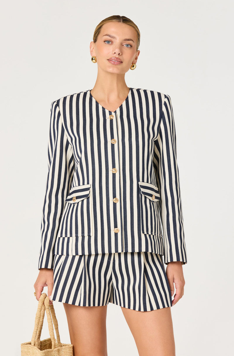 Woman wearing a navy and white vertically striped blazer with gold buttons and matching striped shorts.