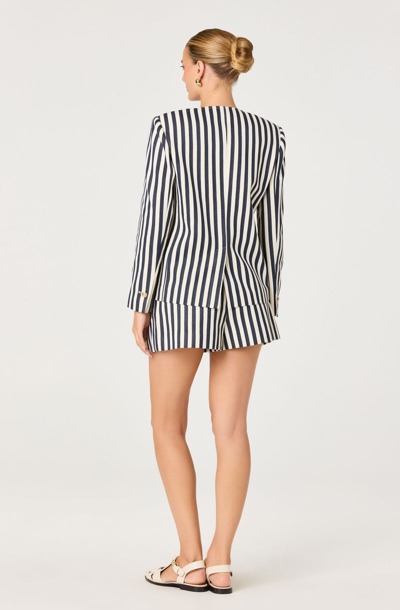 Woman in a navy and white vertically striped blazer with matching shorts, beige sandals.