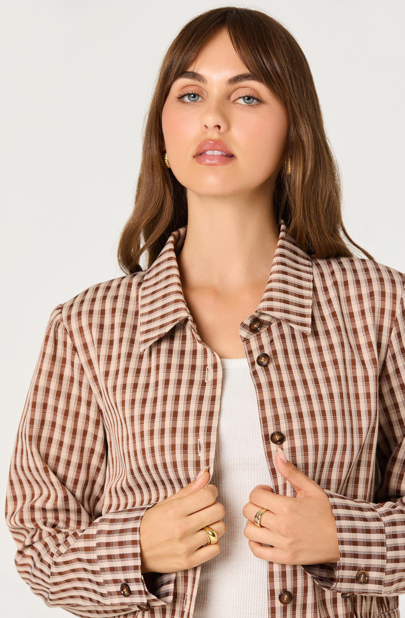 Woman wearing a brown and beige checkered shirt over a white top.