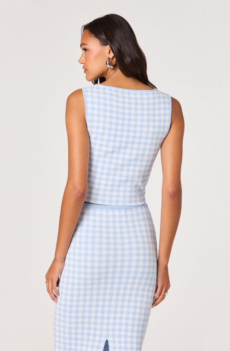 Woman wearing a sleeveless, light blue and white checkered top and matching skirt.