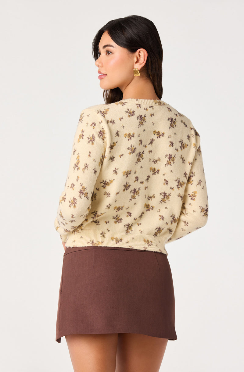 Woman in a cream floral sweater and a brown skirt, side profile.
