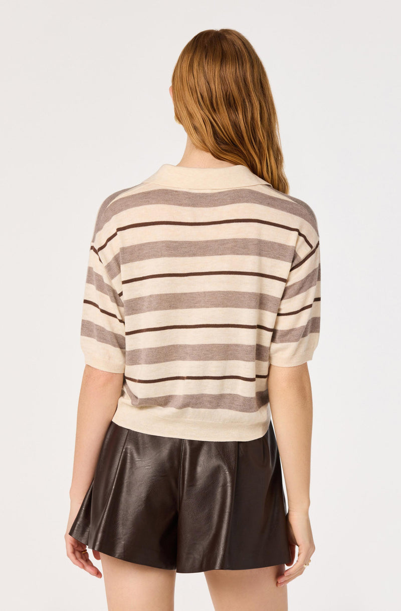Woman wearing a cream and brown striped short-sleeve sweater and black leather shorts.