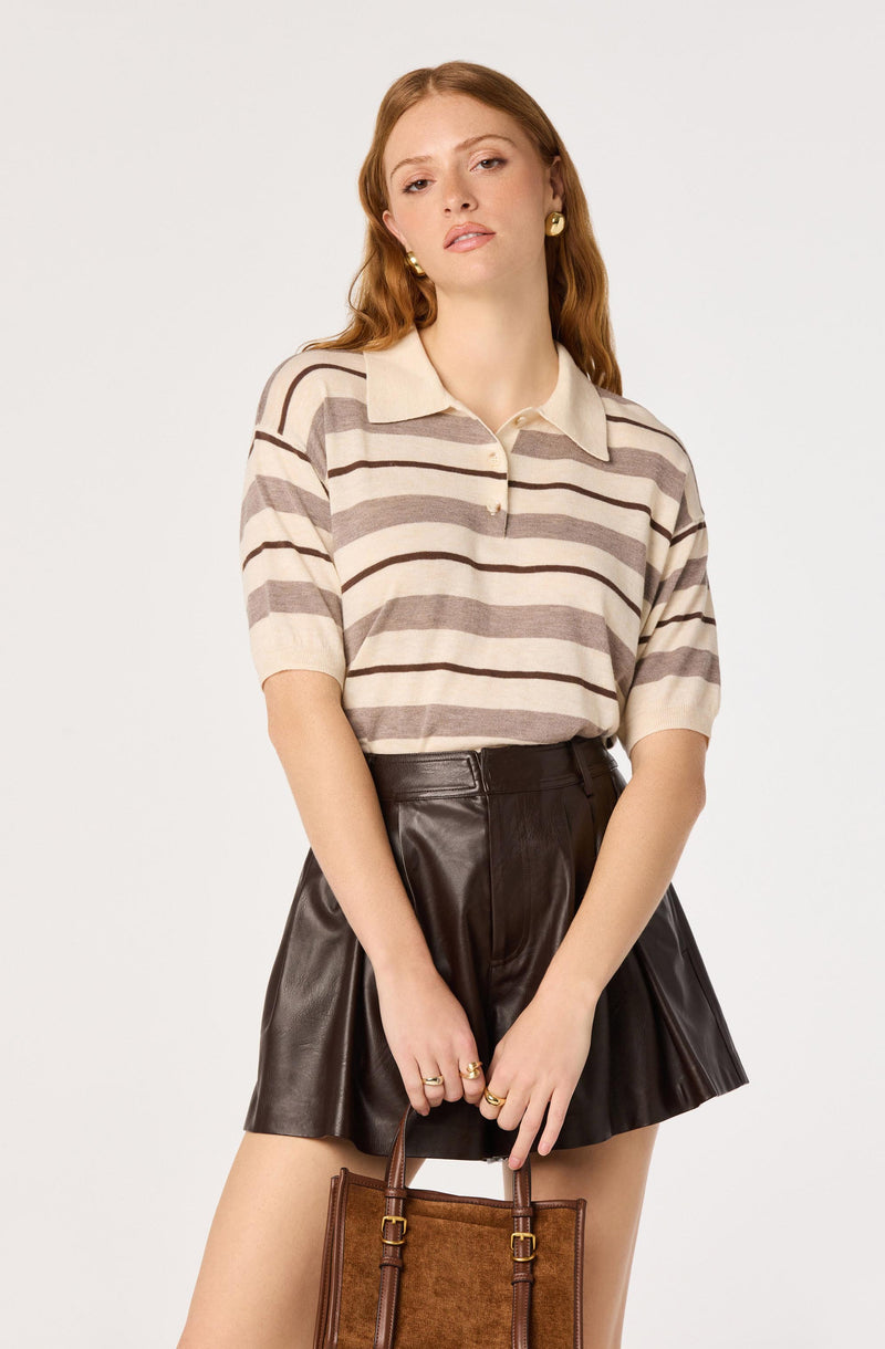 Woman wearing a beige and brown striped polo shirt and a black leather skirt.