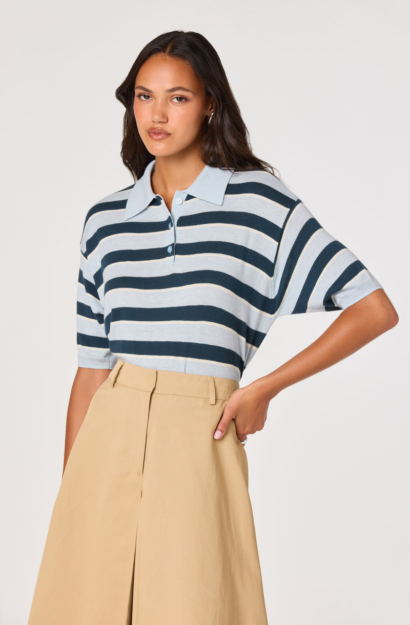 Woman wearing a blue and white striped polo shirt with beige high-waisted wide-leg trousers.