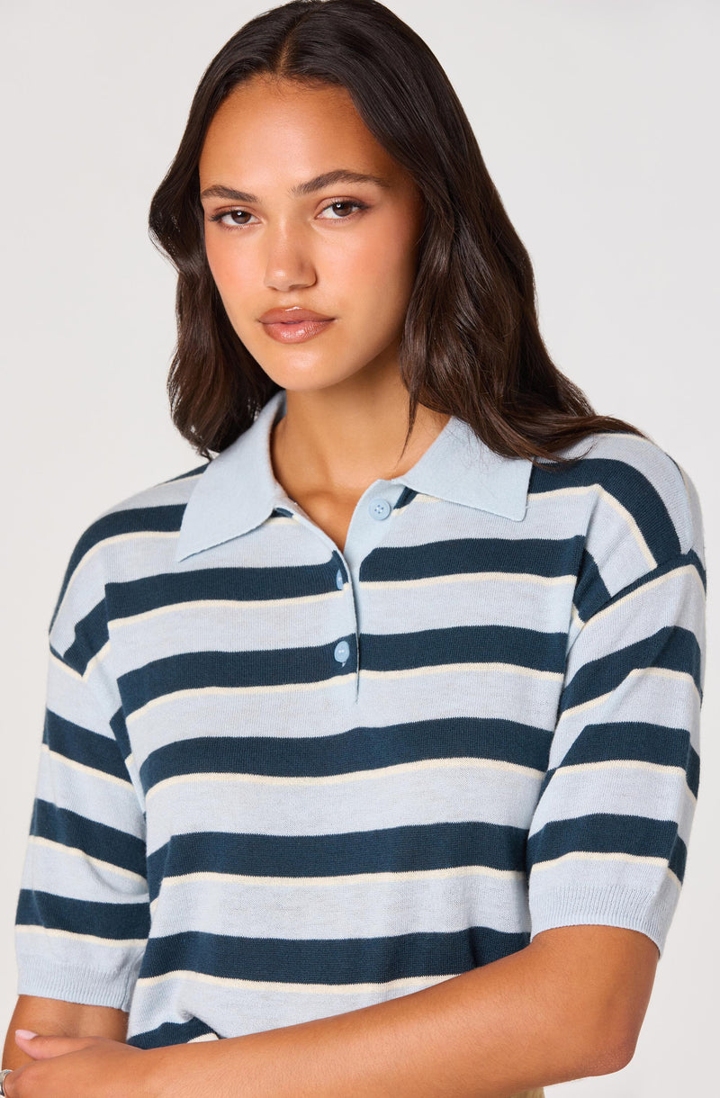 Woman wearing a light blue and navy striped polo shirt.
