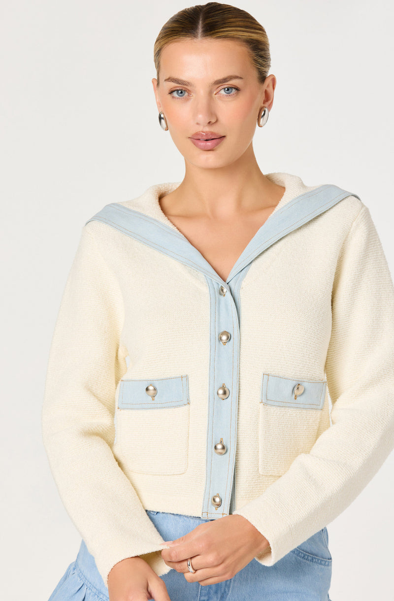Woman in cream and light blue jacket with large buttons and front pockets.