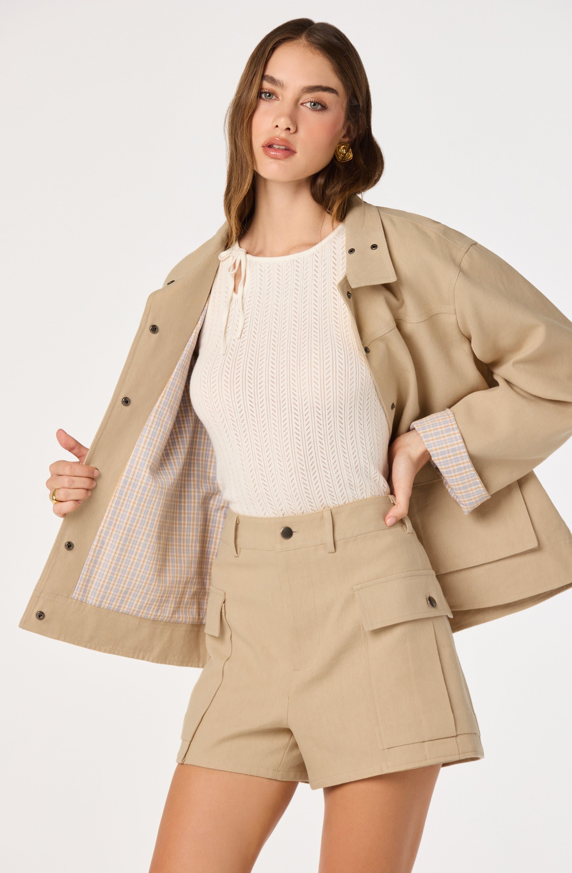 Beige blazer with plaid lining, matching beige shorts, and a cream knit top.
