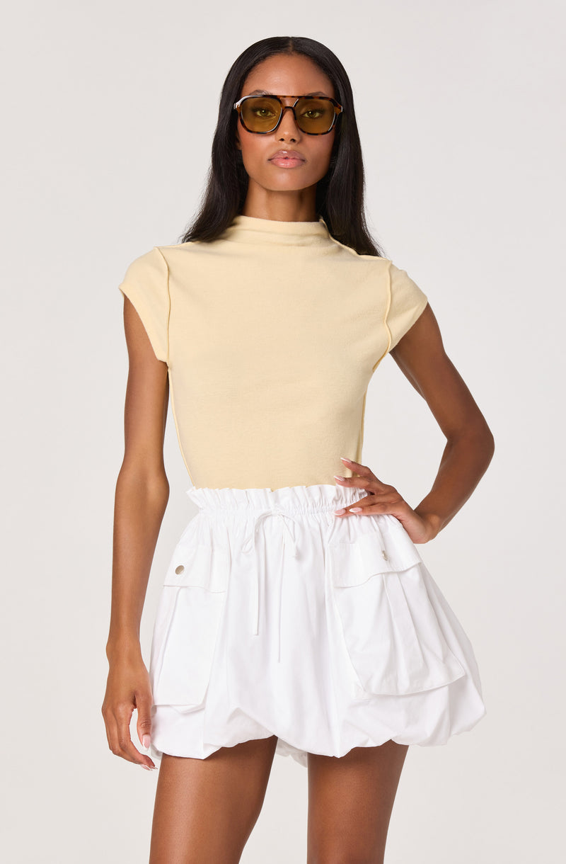 Woman wearing a beige sleeveless top and white ruched cargo shorts.