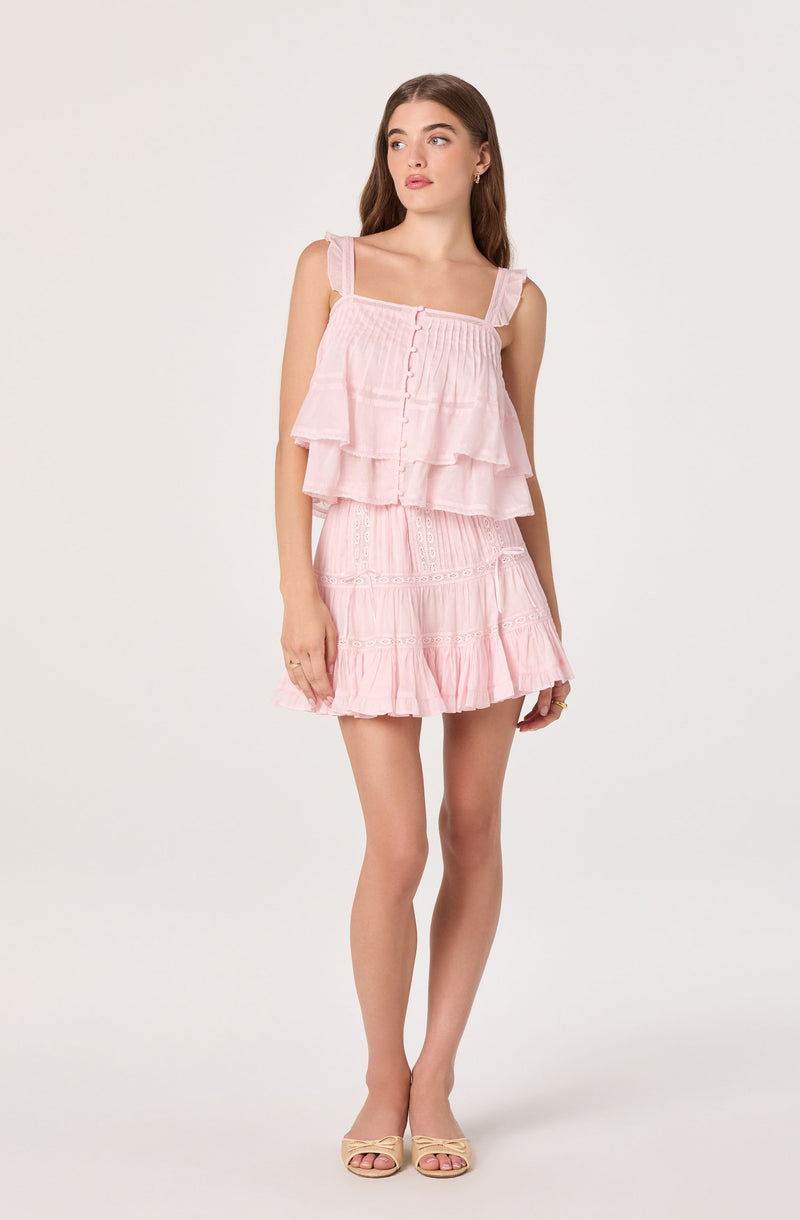 Girl wearing a pink tiered sleeveless dress with straps and ruffle details.