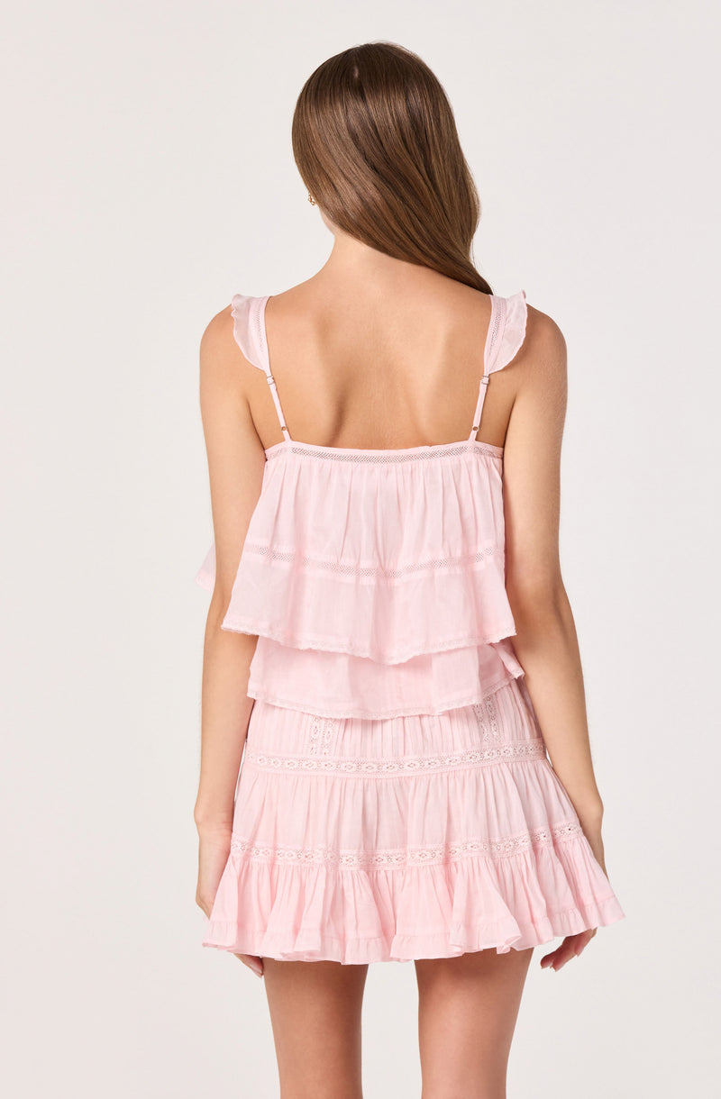 Woman wearing a light pink sleeveless ruffled dress with adjustable straps, layered skirt.