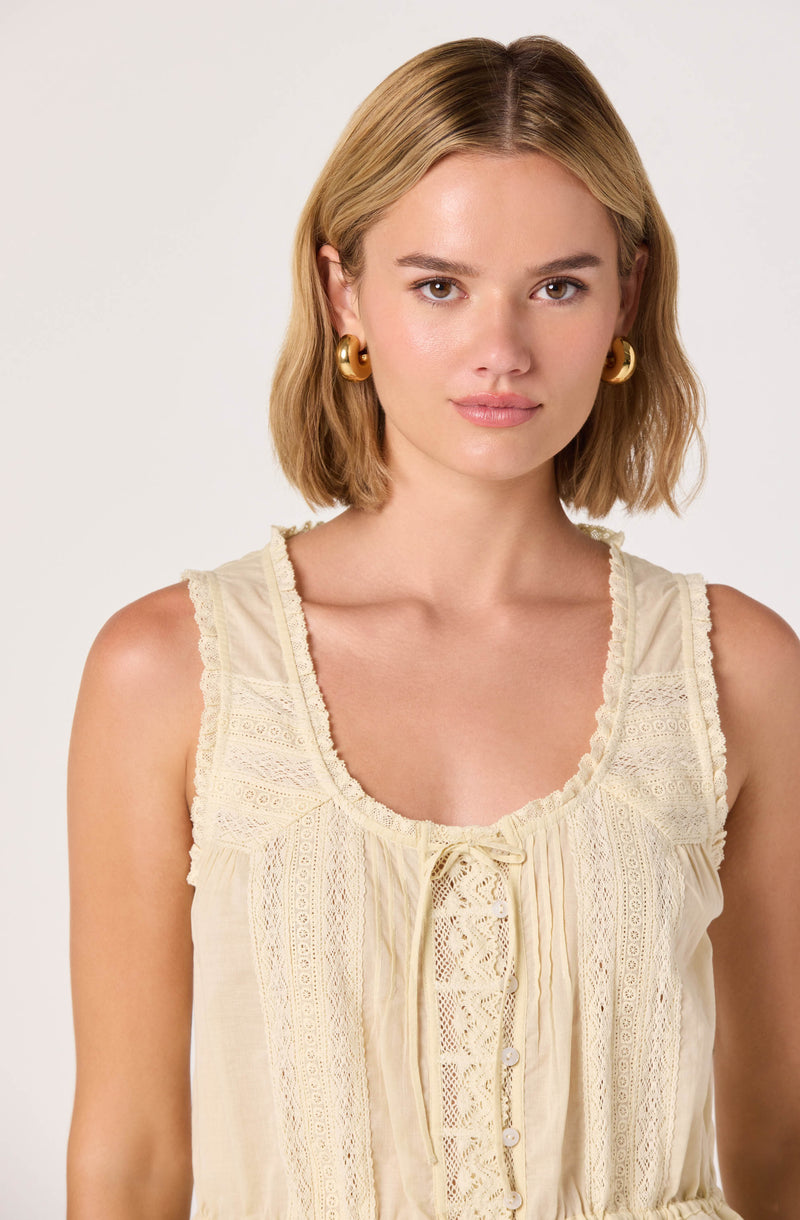 Cream-colored sleeveless top with lace details and a bow tie at the neckline.