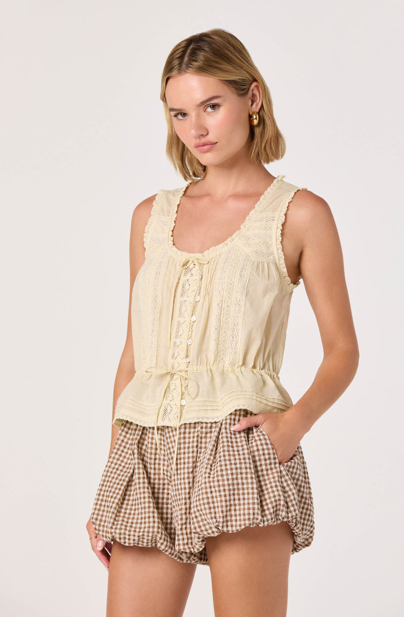 Cream sleeveless top with lace details and buttons, paired with brown gingham shorts.