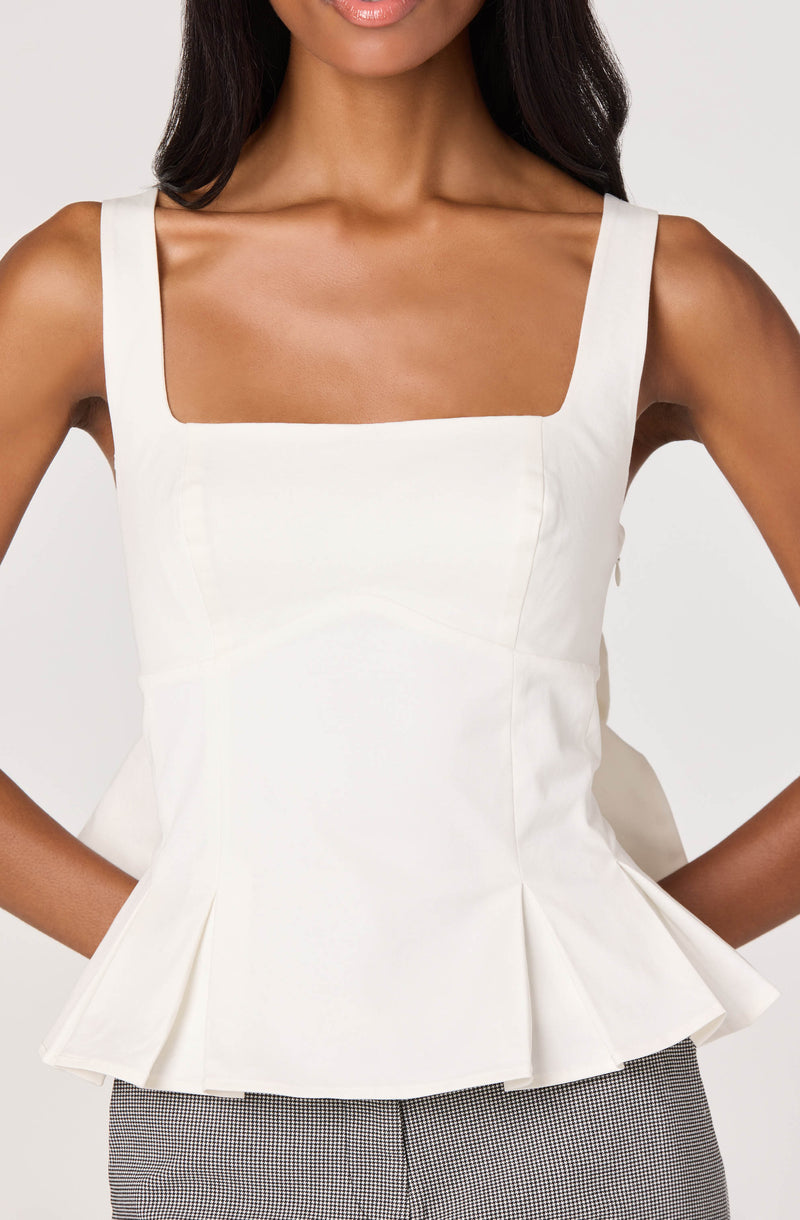 White sleeveless top with wide shoulder straps and a peplum hem.