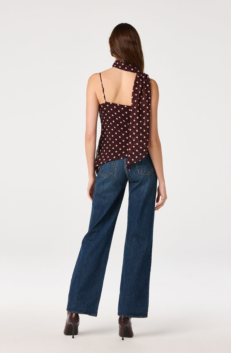 Woman wearing a sleeveless polka dot top with thin straps and a matching polka dot scarf.