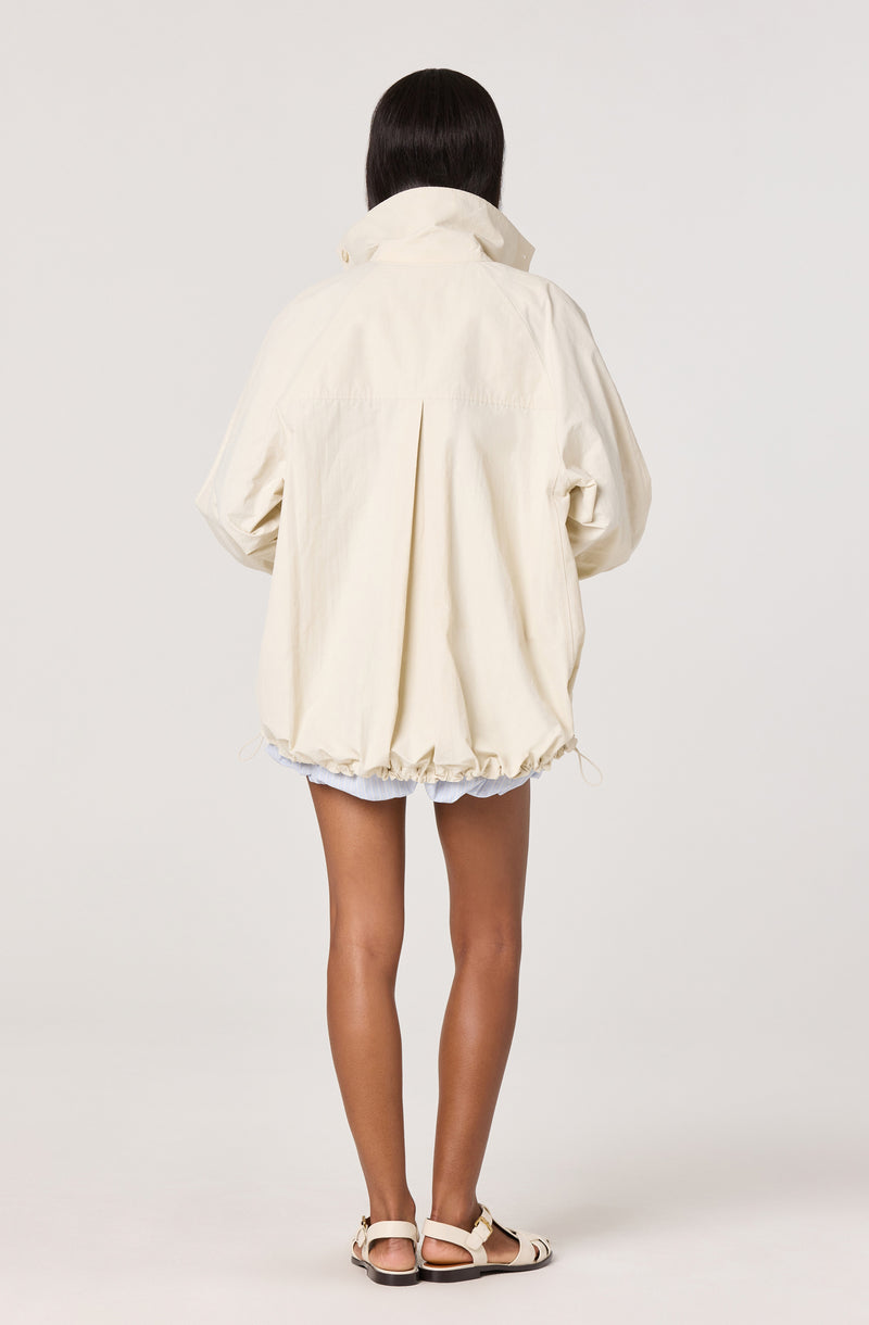 Woman wearing a cream oversized jacket, white shorts, and open-toe sandals.