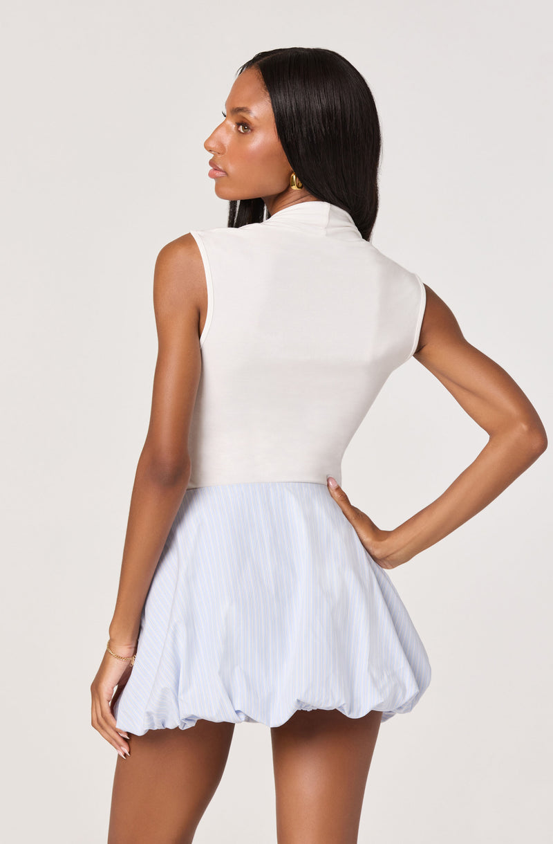 Woman wearing a sleeveless white top and a light blue striped bubble skirt.