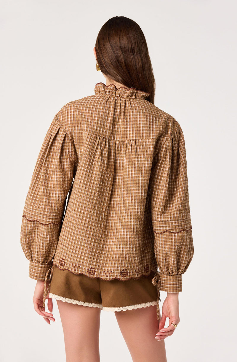 Brown checked long-sleeve blouse with ruffled collar and gathered cuffs, paired with brown shorts.