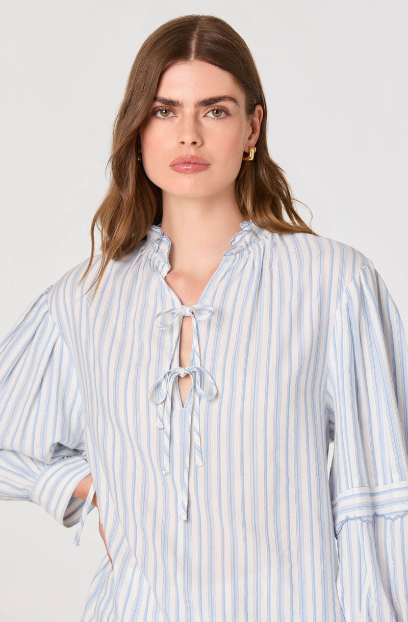 Woman in a light blue and white striped blouse with ruffled collar and bow tie.