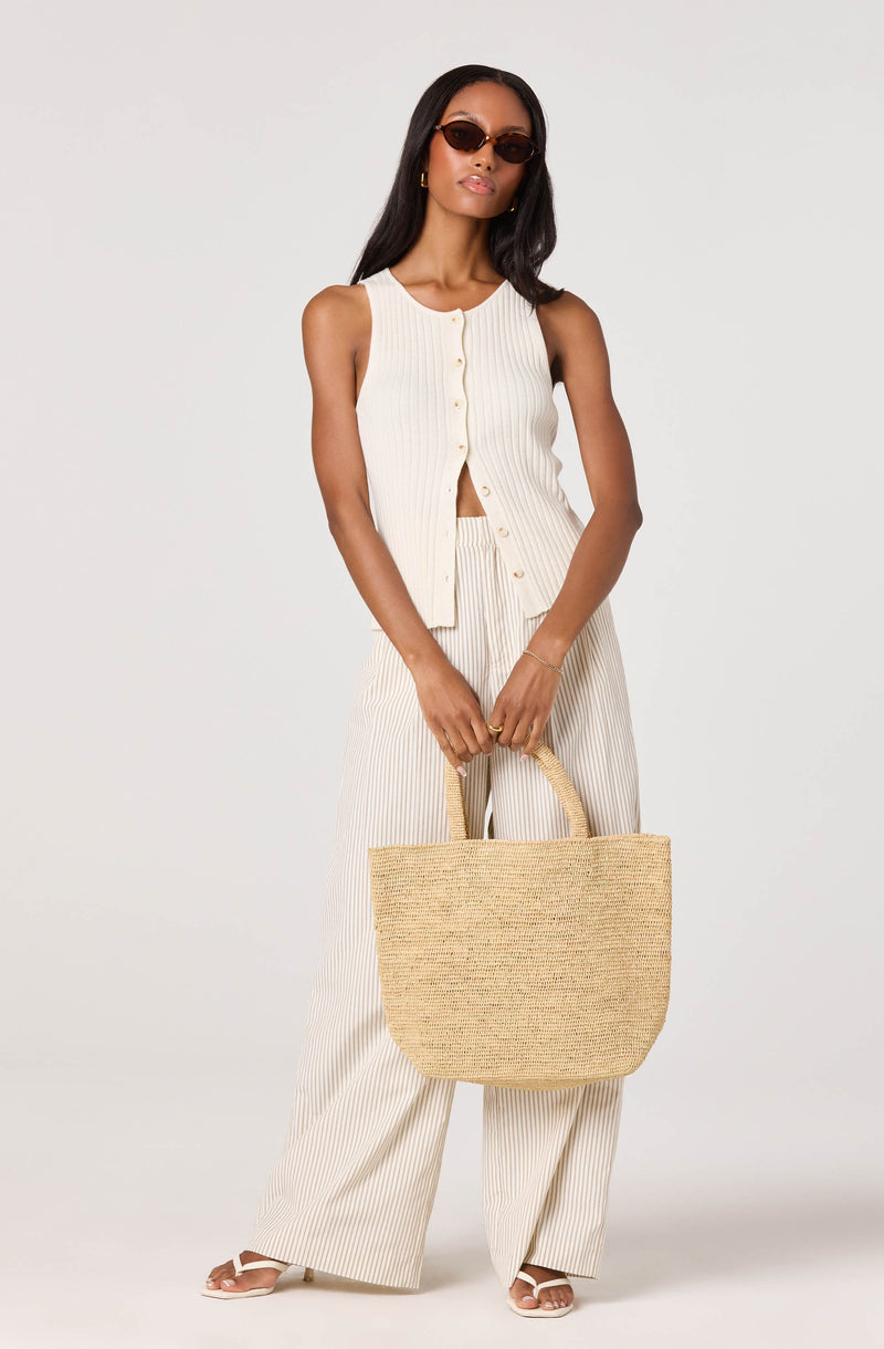 Woman wearing a sleeveless, button-up, cream-colored top with vertical stripes and matching wide-leg pants.